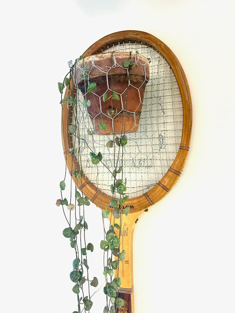 string of hearts hanging from a plant hanger made from a vintage tennis racket